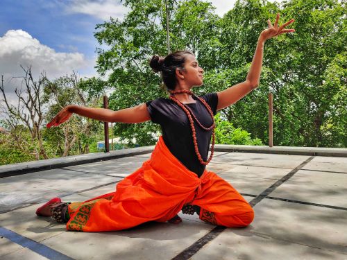 Free A woman gracefully posing in traditional attire against a backdrop of green trees on a sunny day. Stock Photo