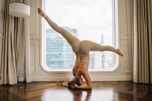 A woman performs a headstand yoga pose indoors, showcasing balance and flexibility.