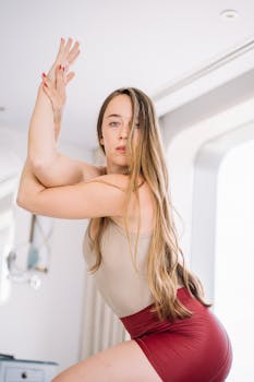 A young woman with long hair practicing a yoga pose indoors for exercise and wellness.