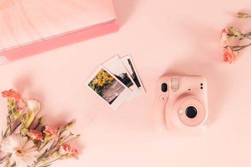 Free Top view of pink Instax camera with floral theme and instant photos on pastel pink background. Stock Photo