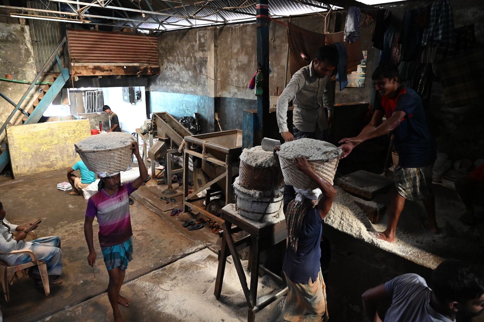 Workers moving grain inside a rice mill