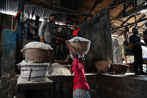 A Man in Red Shirt Carrying a Woven Basket on His Head