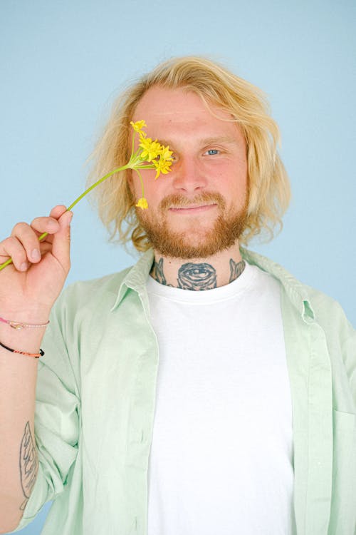 Free Content unshaven man covering eye with yellow flower Stock Photo