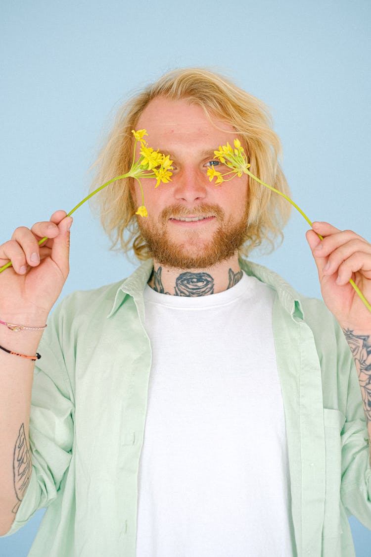 Cheerful Hipster Man Covering Eyes With Blooming Flowers