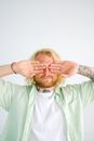 Unrecognizable bearded man covering eyes on white background