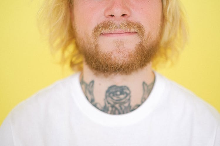 Crop Tattooed Man With Red Beard On Yellow Background