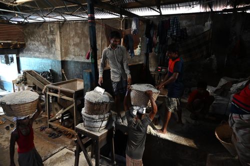 Free Men working in a Chattogram warehouse, practicing traditional manual labor with woven baskets. Stock Photo