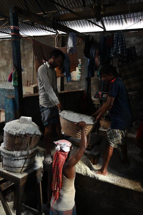 Free Workers process salt in a traditional factory setting in Chattogram, Bangladesh. Stock Photo