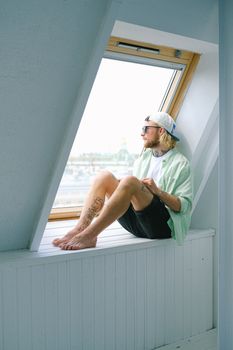 白天，梦幻般的赤脚潮男戴着太阳镜，穿着休闲服向外望去