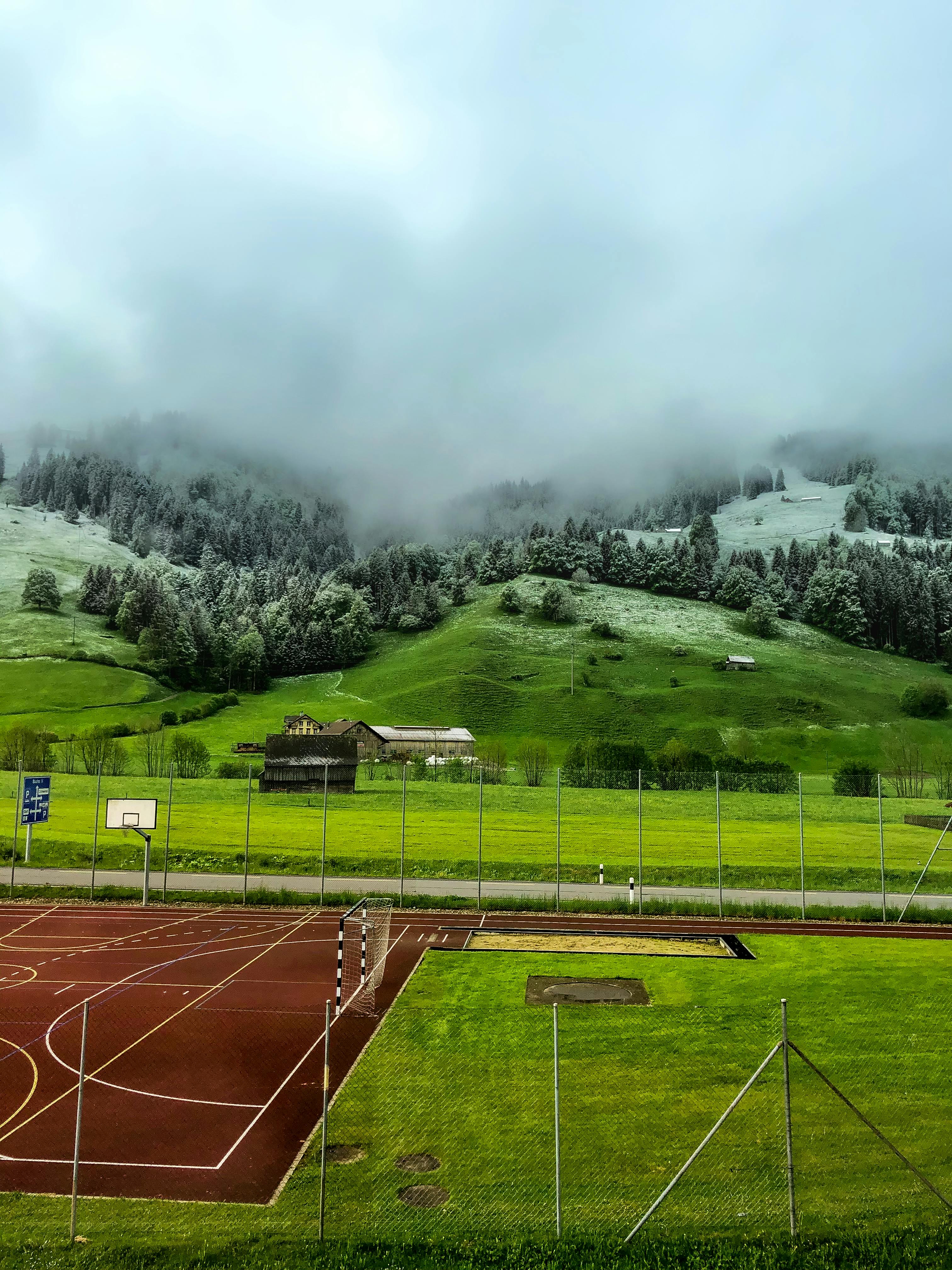 A Basketball Court On Green Grass Field Near Mountain · Free Stock Photo