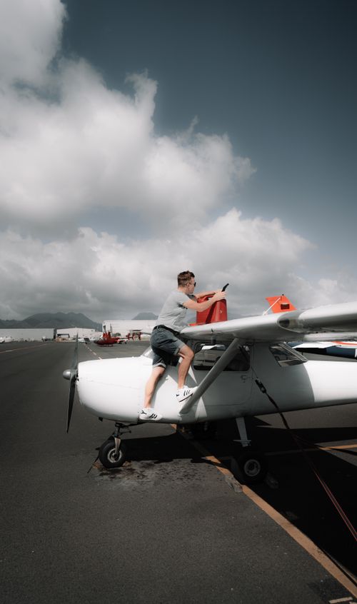 Free Side view full length climbing on propeller jet and pouring fuel into tank on airfield Stock Photo