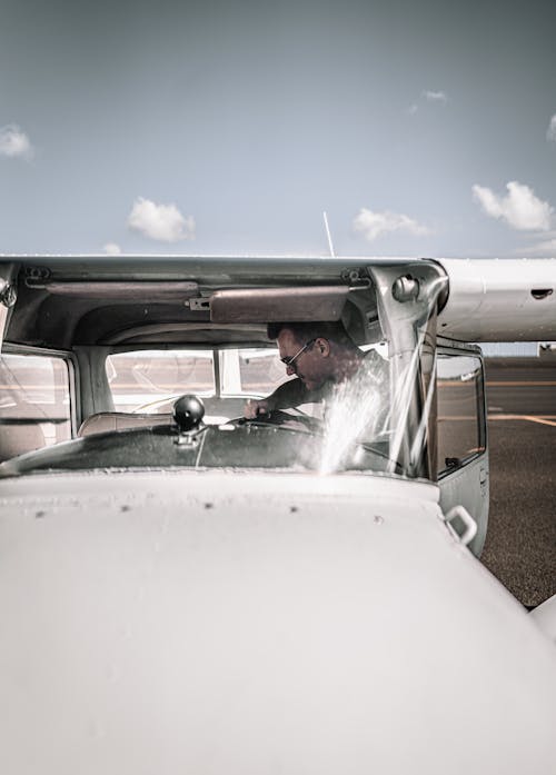 Young man sitting in contemporary two seat aircraft on aerodrome