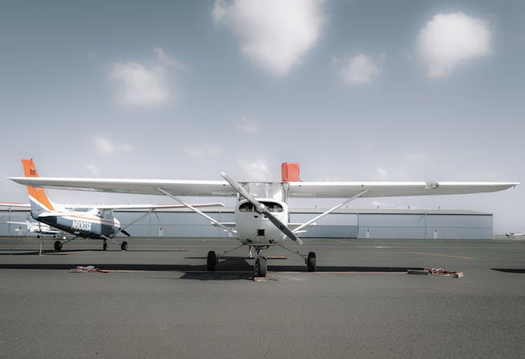 Contemporary High Wing Airplane Parked Near Airport On Sunny Day