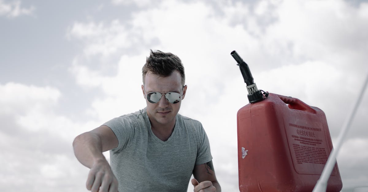 Young concentrated male mechanic in casual clothes and sunglasses pouring fuel into airplane tank before flight