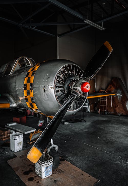 Military monoplane with propeller parked in dark hangar during repair works at night