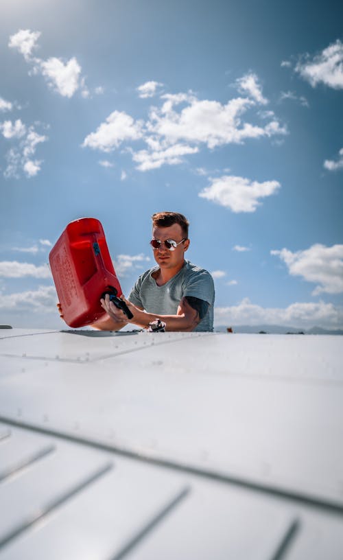 Free Young man pouring fuel into aircraft tank against blue sky Stock Photo