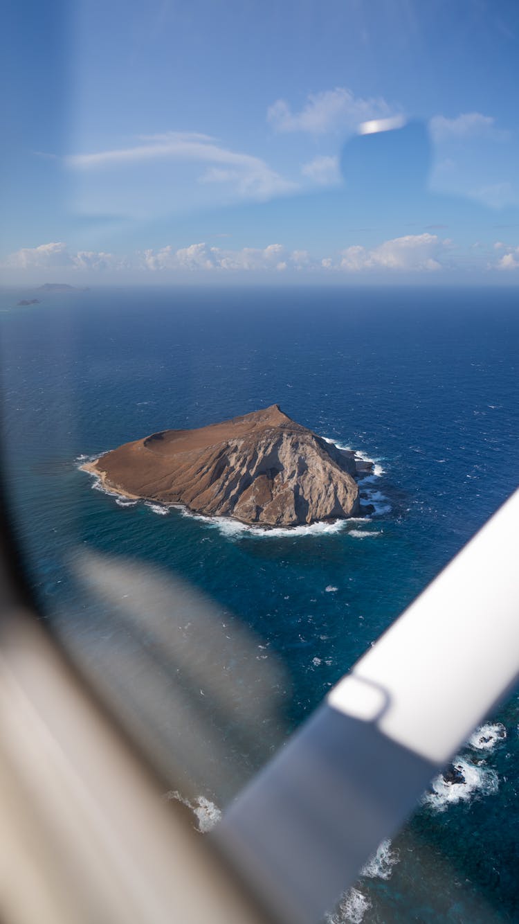 Modern Plane Flying Over Volcanic Island Washed By Wavy Sea