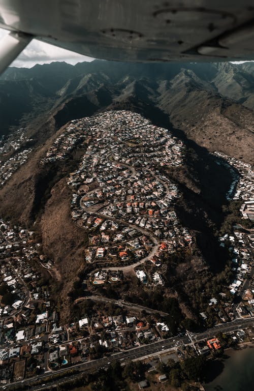 Airplane flying over town located in volcanic terrain
