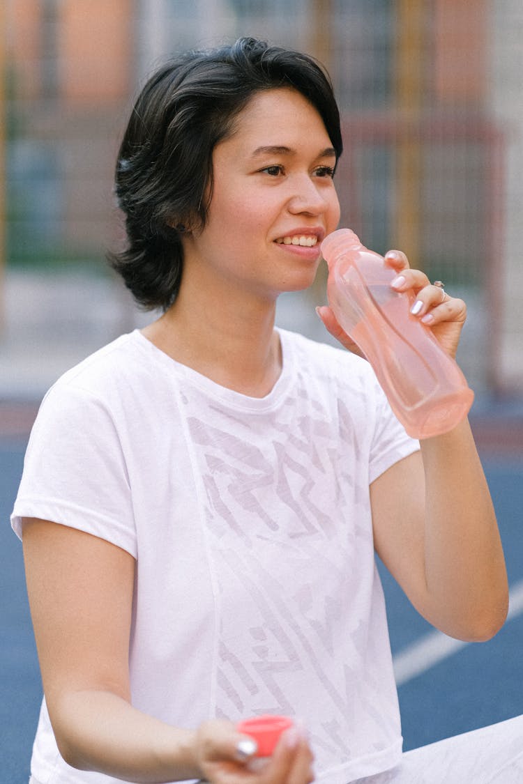 Female Drinking Water On Sports Ground