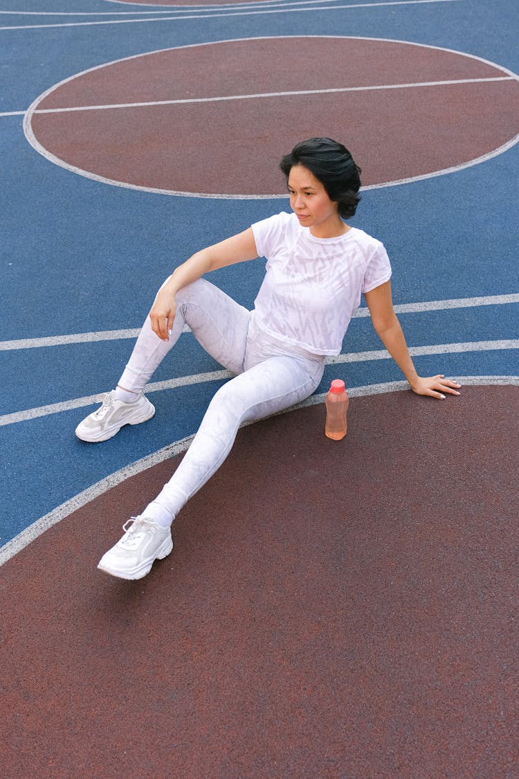 Female Sitting On Sports Ground With Water Bottle