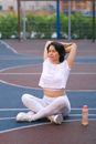 一名穿着运动服的年轻女子在白天双腿交叉，靠近栅栏边的瓶子进行训练