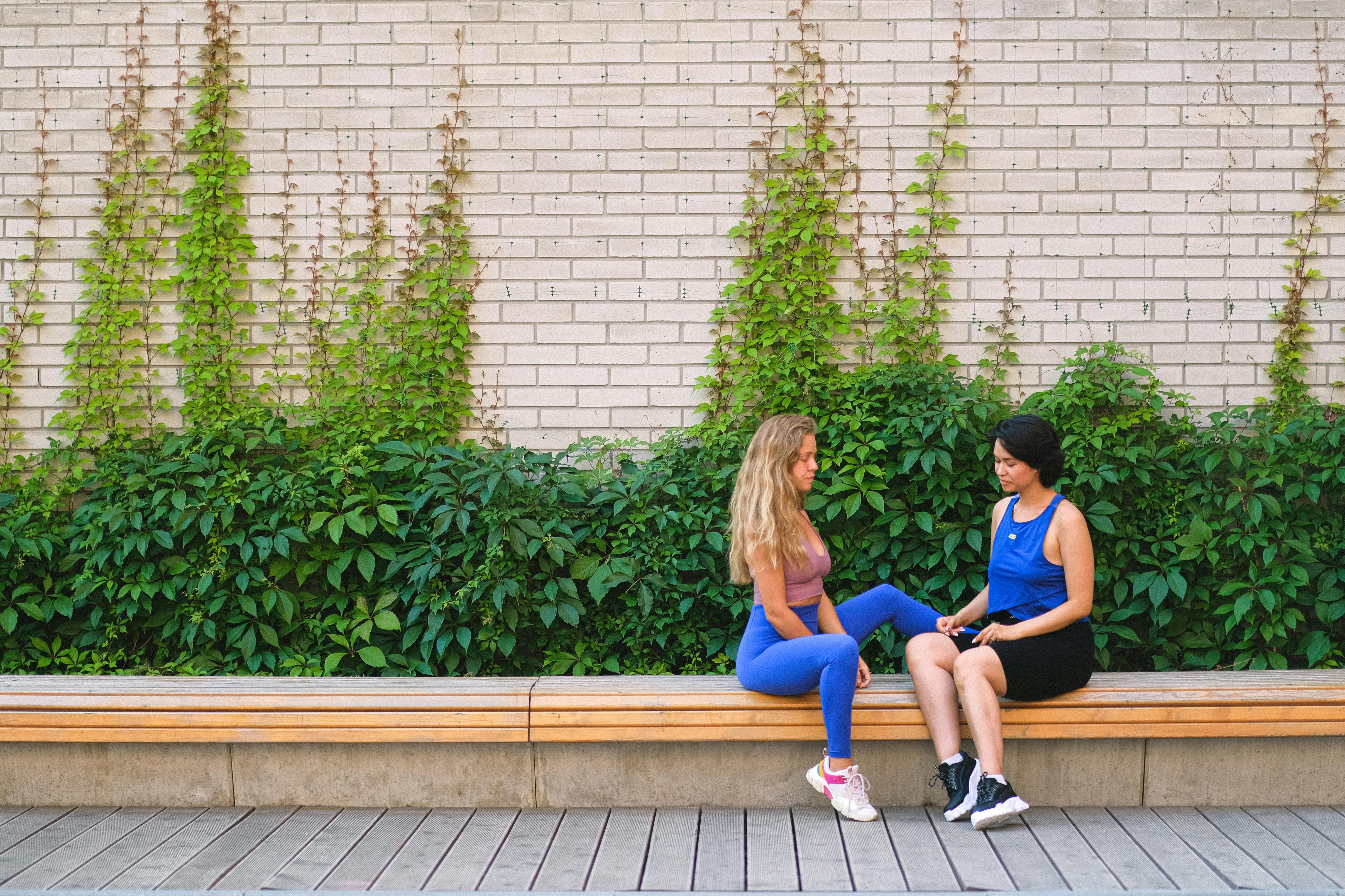 sportswomen having conversation on bench near wall