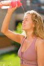 Sporty woman pouring water on face in park