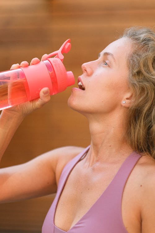 Free Crop tired sportswoman drinking water during training Stock Photo