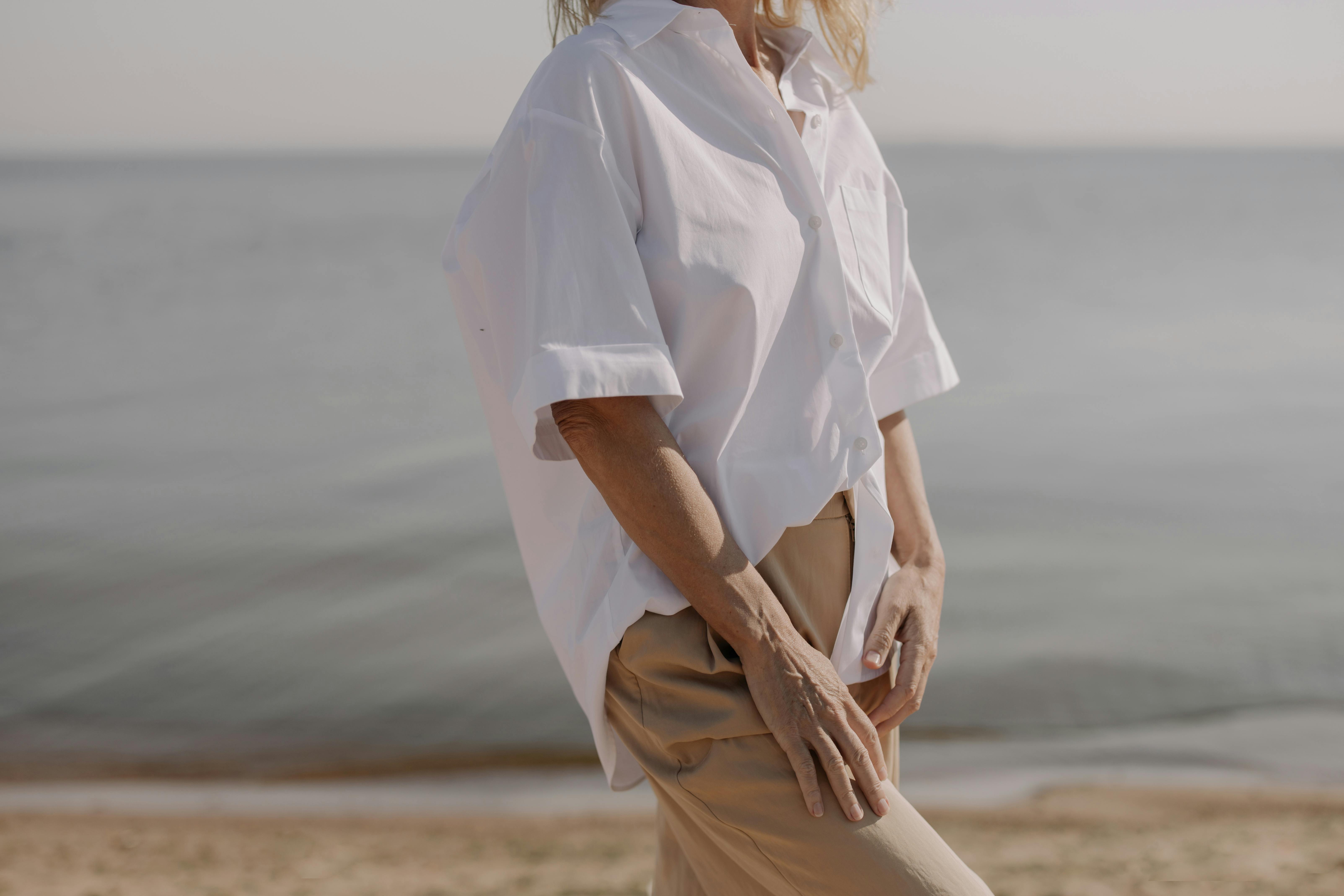 一位穿着经典白衬衫的优雅女子优雅地站在宁静的海边