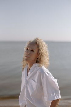 一位优雅的资深女士在海滩上摆着姿势，散发着时尚与自信