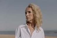 一位穿着白色衬衫的资深女性，肖像立在宁静的海滩上