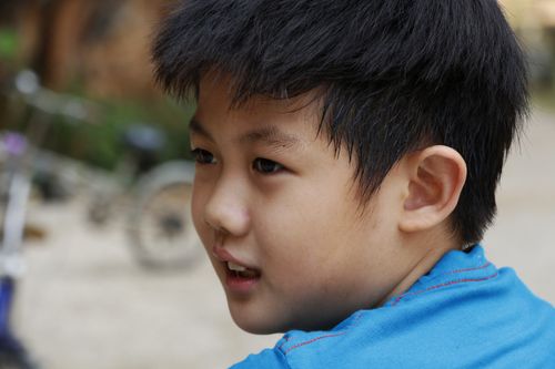 Free Close-up of a cute Asian boy smiling outdoors, captured in natural light. Stock Photo