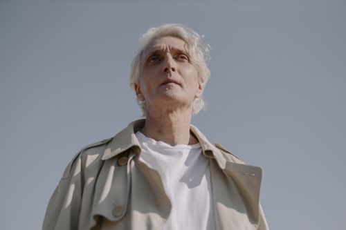 Free Low angle portrait of an elderly man in a grey coat against a clear sky, evoking serenity and wisdom. Stock Photo