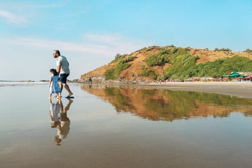 Unrecognizable caring father walking on coast with daughter