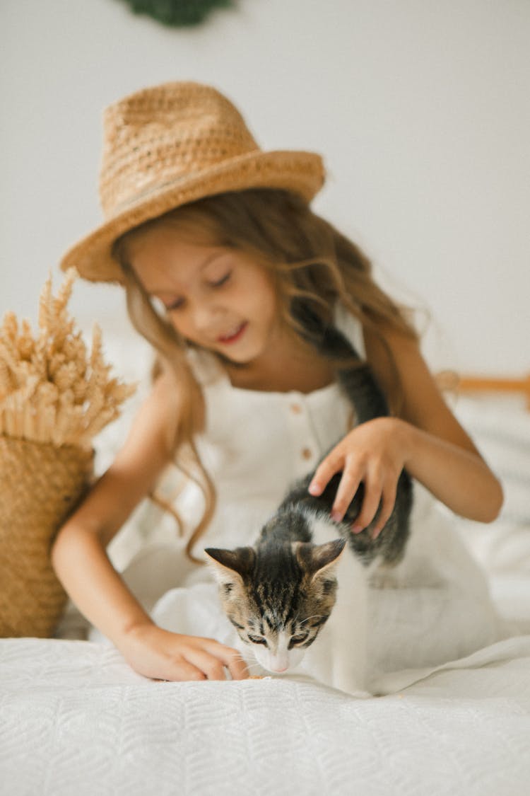 Girl In A Straw Hat Touching A Cat