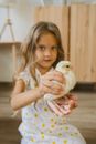 Girl in White and Blue Polka Dot Shirt Holding White Chick