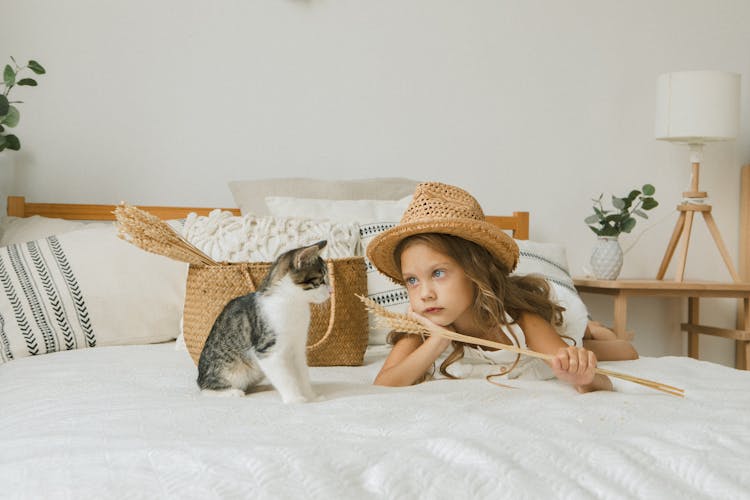 Girl In Hat With Cat On Bed