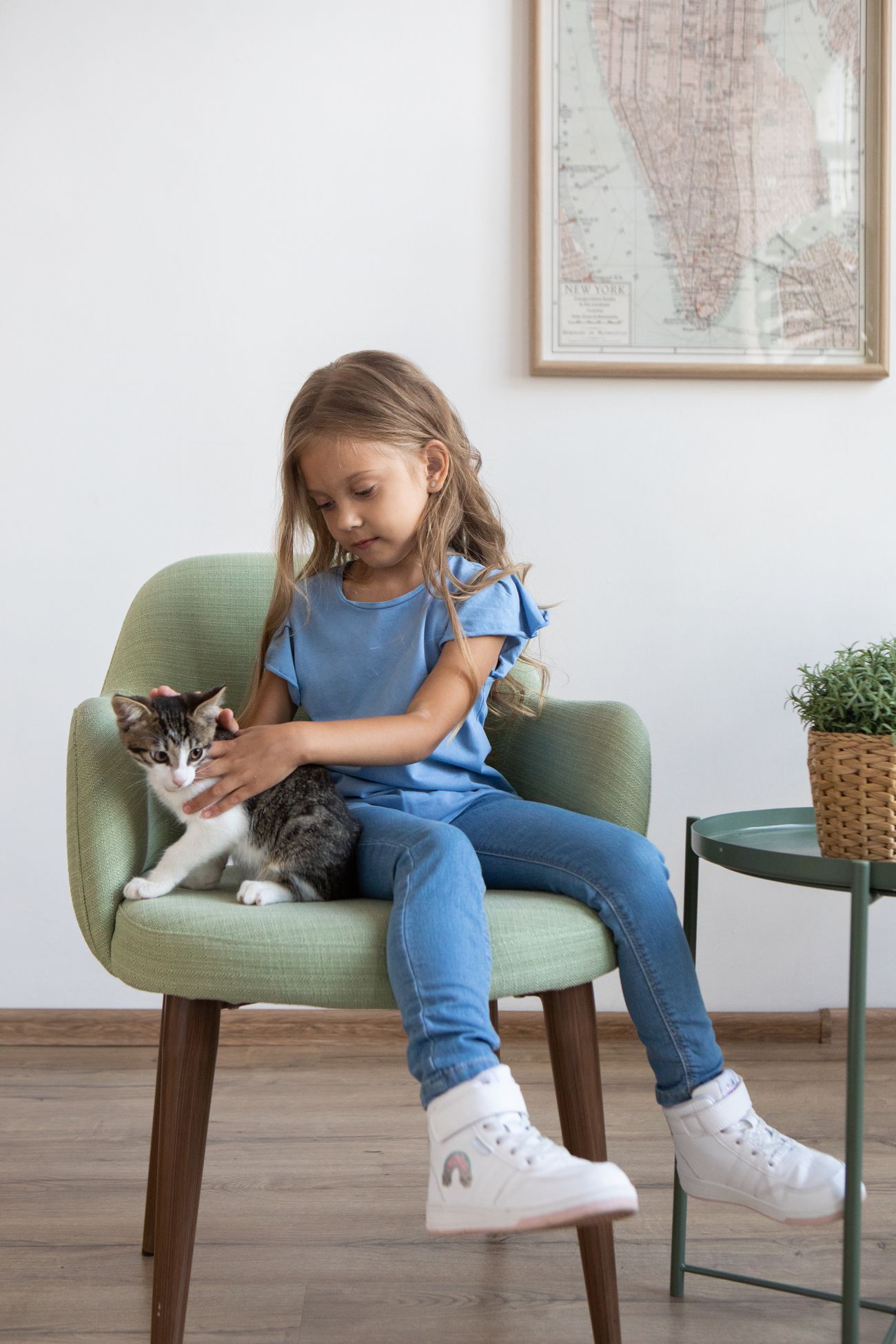 椅子に座る子どもが猫をなでている室内