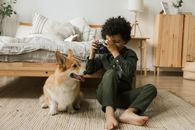 孩子带着相机和柯基犬，在舒适的卧室里，气氛温暖而轻松