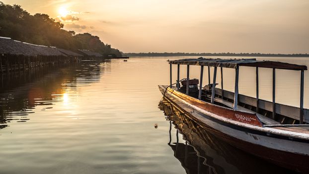 Tranquil scene of a wooden boat on a lake at sunset in Siem Reap, Cambodia.