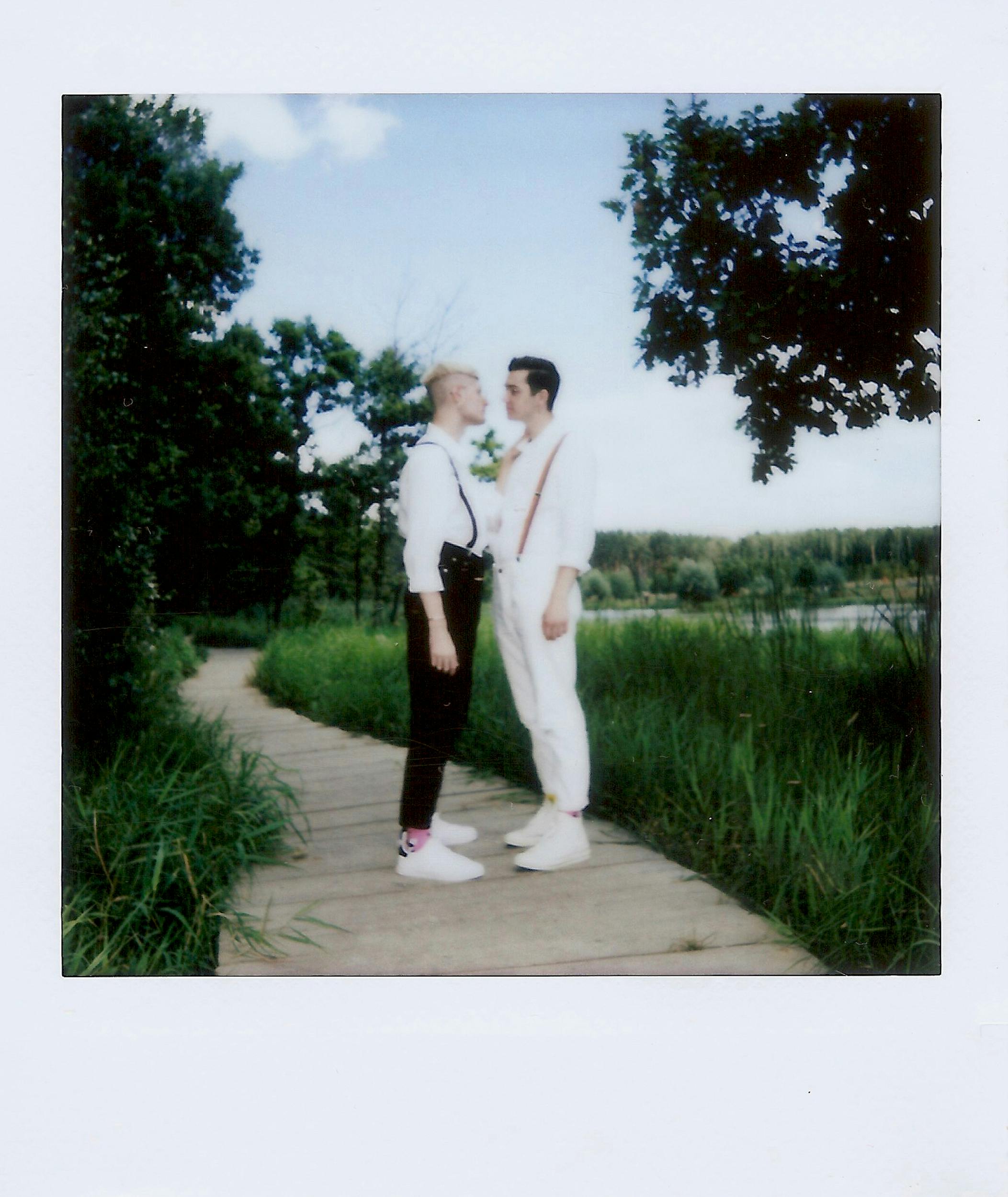 A loving moment captured between a gay couple outdoors on a sunny day.