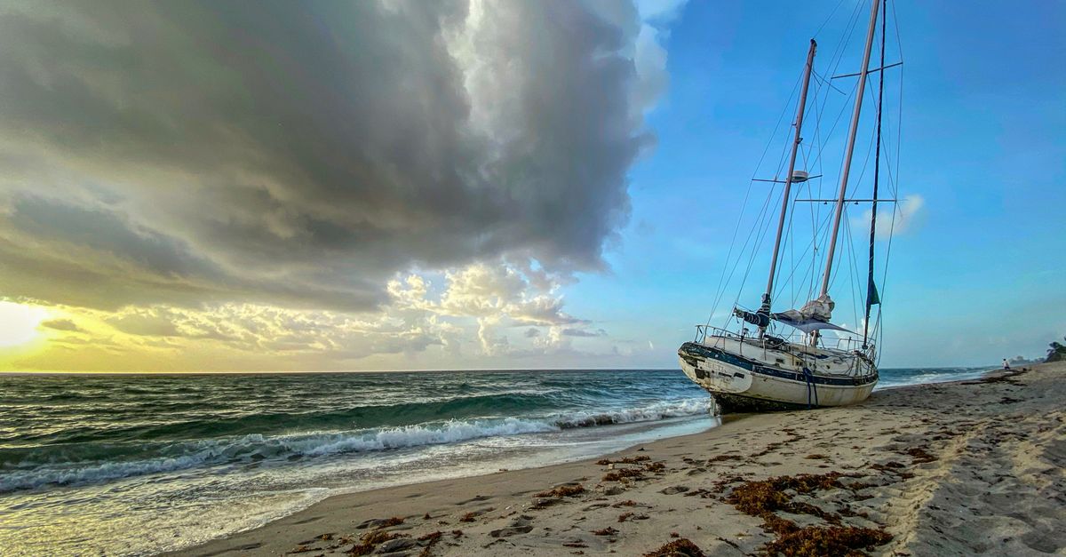 A sailboat stranded on Highland Beach with a dramatic sunrise sky.