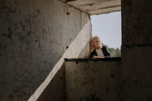 Free Elegant woman poses thoughtfully in sunlight at an abandoned building. Stock Photo
