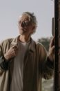 一位白发老人穿着外套、戴着眼镜站在门口