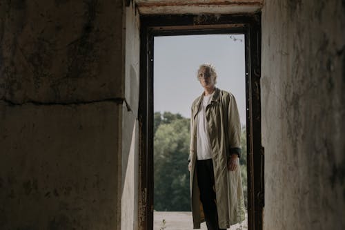 Senior Man in White Shirt and Beige Trench Coat Standing on a Doorway