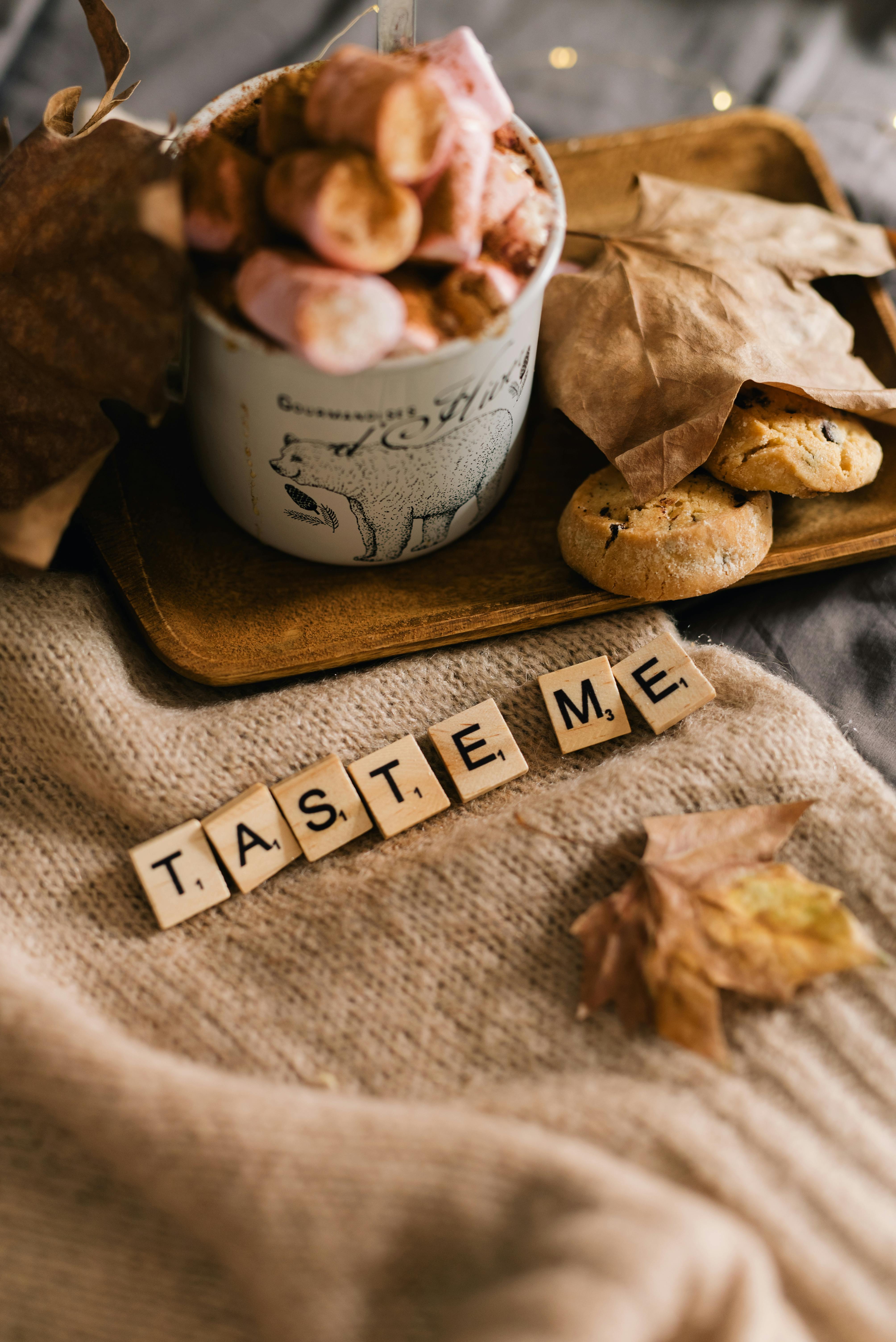 Warm autumn-themed setup with marshmallows and cookies, inviting with 'Taste Me' letters.