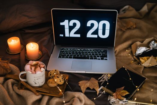 A cozy workspace with a laptop, candles, and a cup of hot chocolate, perfect for autumn evenings.