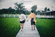 Man in Yellow Shirt and Black Shorts Holding Hands With Woman in Black and White Long