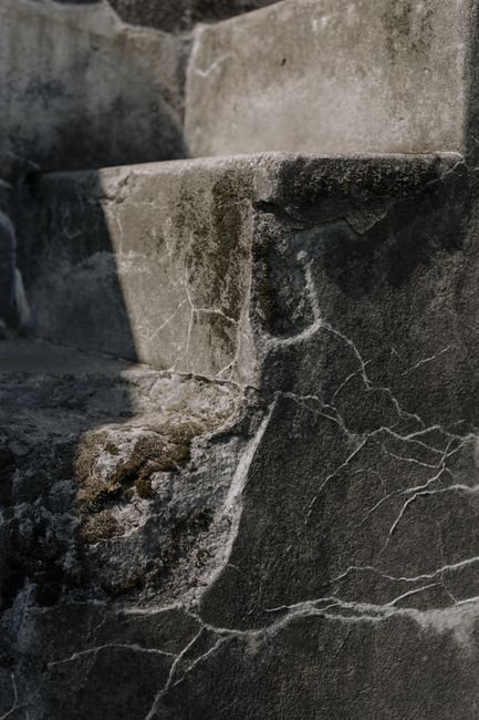 Close-up shot of old, weathered concrete steps displaying intricate textures and cracks.