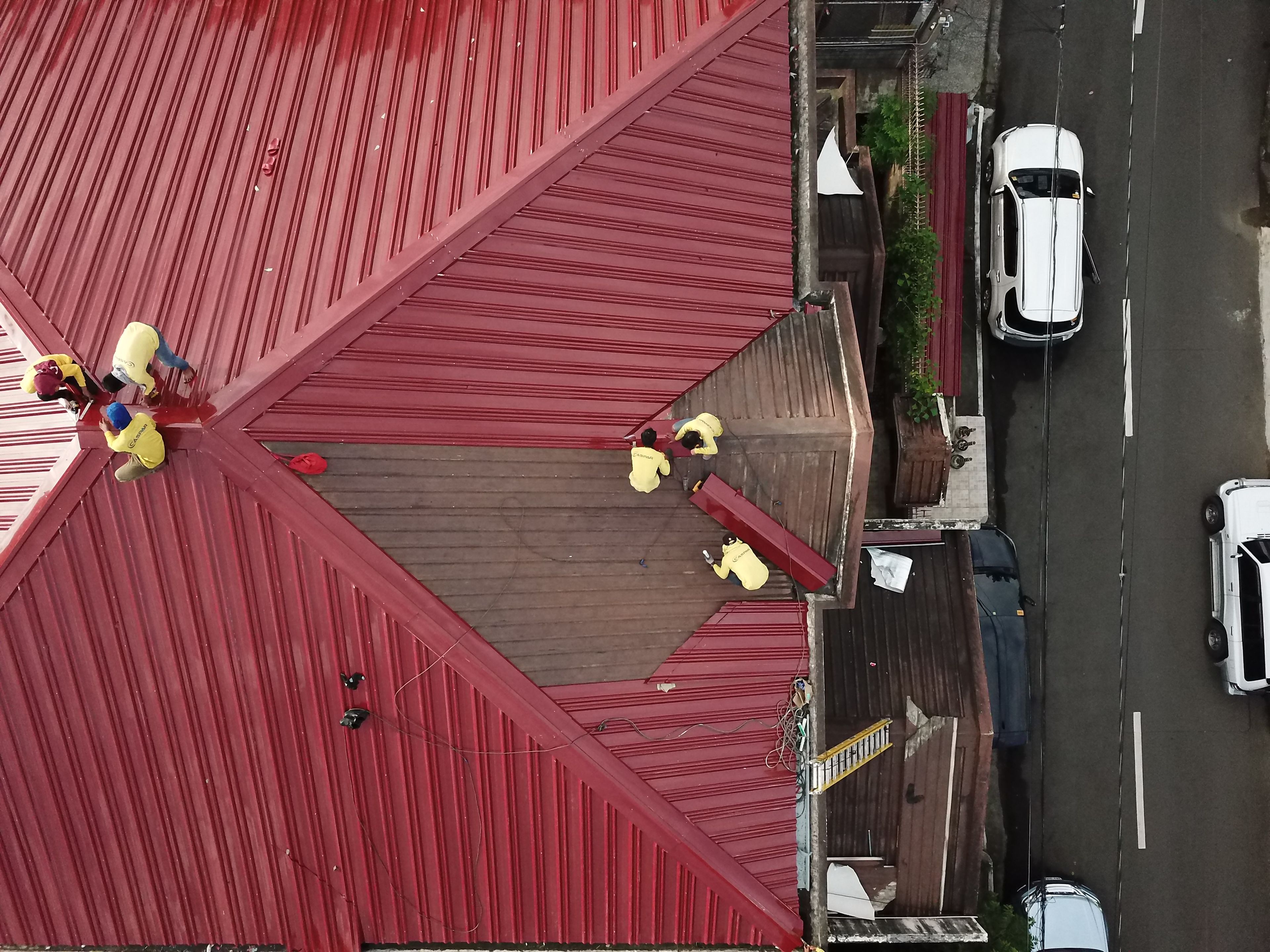 Overhead view of a crew working across a red metal roof
